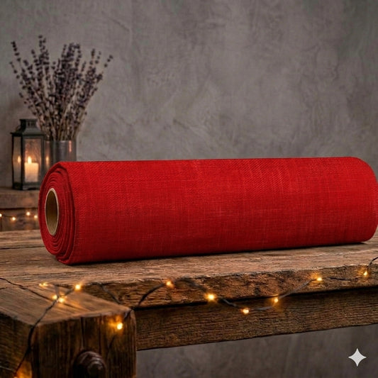 Eine aufgerollte Stoffrolle des roten French Terry Allover-Stoffs „Feurige Struktur“ von Niggi's Handmade liegt auf einem rustikalen Holztisch. Das leuchtend rote Design zeigt eine melierte Textur im Denim- und Leinen-Look. Im gemütlichen Hintergrund stehen getrockneter Lavendel und eine Laterne mit brennender Kerze, umrahmt von einer warm leuchtenden Lichterkette im Vordergrund.